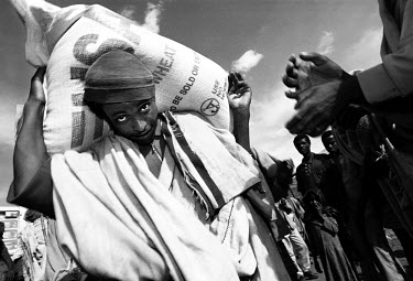 Famine. Workers carrying bags of American wheat from the United Nations WFP (World Food Programme) from the store to the distribution site at an open space outside Sirer village where people from the...