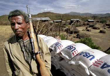 Famine. Local policeman with gun on guard at a distribution site in Sirer village where American wheat from the United Nations WFP (World Food Programme) is being handed out. Many people have left the...