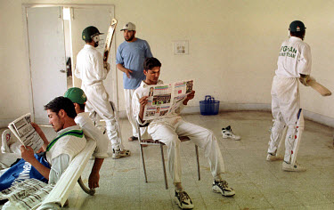 The Afghan national cricket team in their changing room preparing to bat against a team from Swat. Some team members read up on news of the war in neighbouring Afghanistan.