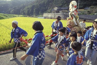 Children carry a straw shrine and offer thanks to the Gods for the October rice harvest.