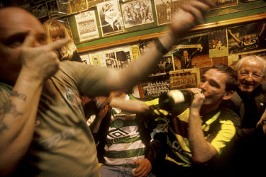 Raucous Celtic supporters mime the shooting of a rifle in Baird's Bar, a famous pub in Glasgow's East End decorated with Celtic memorabilia.The 'Old Firm' rivalry between Celtic and Rangers is renown...