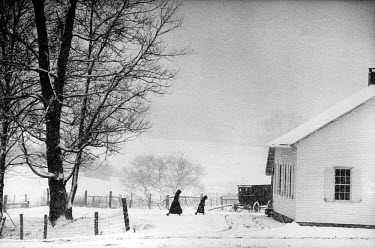 A snowy Sunday, the day of prayer for the Amish community. Families come to church by horse and carriage. After putting out the horses, they complete the last part of the journey on foot, the women an...