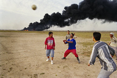 Local villagers play football in front of a ditch filled with oil and set on fire. Initially set in an attempt to prevent invading planes from locating their targets, many of these fires raged on for...