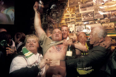 Raucous Celtic supporters celebrating in Baird's Bar, a famous pub in Glasgow's East End decorated with Celtic memorabilia.The 'Old Firm' rivalry between Celtic and Rangers is renowned as the world's...