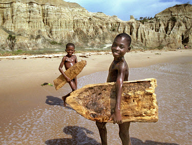 Children attempt to surf on hand-made surf boards, carved out of driftwood. They were inspired by watching foreigners surfing on the beaches near the capital city.