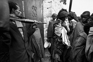 A guard forces back refugees from a feeding centre during the 1992 famine in Somalia, caused by the civil war. In 1991 President Barre was overthrown by opposing clans, but they failed to agree on a r...