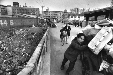 A woman pushing a heavily-laden cart of waste collected for recycling. Shenyang is one of the main heavy industry bases in China. Today the factories are not profitable any more and most of them are c...