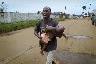Father carrying his dead child. A barrage of mortar fire, presumed to come from Lurd rebel positions, struck Mamba Point in downtown Monrovia. Dozens were killed and many more wounded.~The ongoing con...