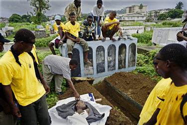 A militia member killed in fighting at the Waterside Market is buried in Monrovia's central cemetery. His unit, the Marine commandos, wear yellow T-shirts as their uniform.~The ongoing conflict in Lib...