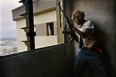 Frontline position. A government fighter, wearing a wig for supernatural protection, peers out from the former headquarters of the National Bank of Liberia. A block or so away are LURD rebel positions...