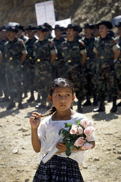 Kekchki Indian girl at a ceremony for a new road, with soldiers in the background.