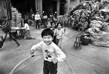 Children playing in front of piles of recycled computer material. Every year Guiyu takes in more than a million tons of computer waste, imported primarily from the United States, Japan and South Korea...
