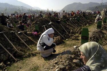 Women grieve at the graves of their loved ones killed during the 1995 Srebrenica massacre.~                                War Crimes.