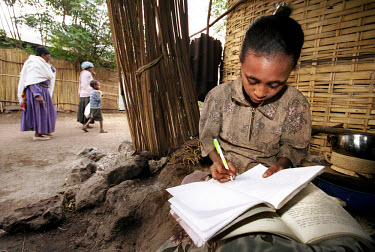 Yeshimbet Gashiye doing her homework, outside her home in a slum area of Bahir Dar, near Lake Tana.