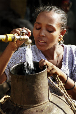 Woman filling a container with water at a community tap in a slum area of Bahir Dar, near Lake Tana.