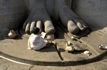 Hindu child worshipping at feet of statue.