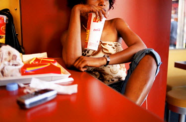 Jessica, a Nigerian sex worker, eating a meal at McDonalds. Thousands of Nigerian women are trafficked into Western Europe every year. They are forced to work in the sex industry to pay back debts of...