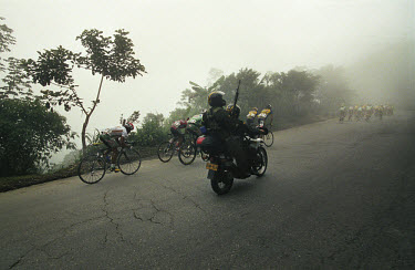 An armed escort accompanies competitors on a mountain stage in the Veulta a Colombia. The 53rd Vuelta a Colombia took place against a backdrop of civil war and violence. The bicycle race is guarded al...
