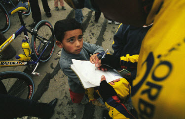 A boy gets the autograph of a competitor in the Vuelta a Colombia. The 53rd Vuelta a Colombia took place against a backdrop of civil war and violence. The bicycle race is guarded along its entire rout...