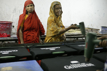 Women workers drying screen printed Guinness t-shirts with hand held dryers in a garment factory.  Factories such as these fail to comply with the most basic health and safety regulations.  90% of the...