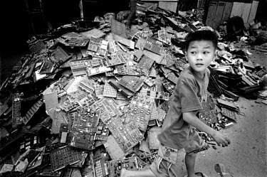 A boy runs past a heap of circuit boards in an alley. Every year Guiyu takes in more than a million tons of computer waste, imported from all over the world. About 40,000 local farmers and 100,000 mi...