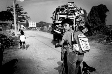 On her way to school a girl passes a truck laden with computer hardware. Every year Guiyu takes in more than a million tons of computer waste, imported from all over the world. About 40,000 local far...