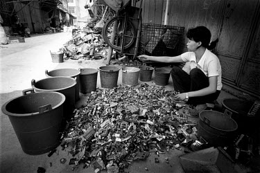 A woman sorts through chips recovered from old computers. Every year Guiyu takes in more than a million tons of computer waste, imported from all over the world. About 40,000 local farmers and 100,00...
