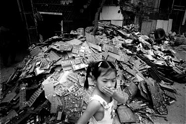A girl passes a heap of circuit boards in an alley, holding her nose because of the strong smell of tin solder. Every year Guiyu takes in more than a million tons of computer waste, imported from all...