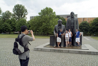 Tourists pose for photographs next to statues of Karl Marx and Friedrich Engels in Marx-Engels Platz.