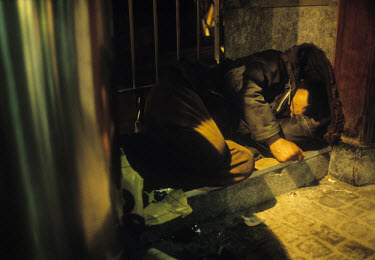 Homeless man sleeping in a doorway.