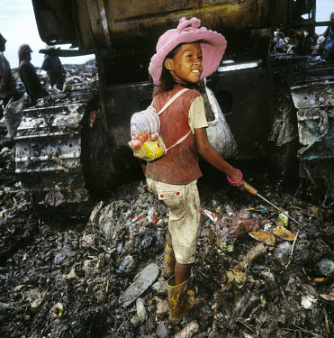 Child labour.  A young girl works collecting metal and plastic from the city's main rubbish dump.