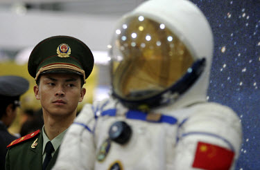 A People's Liberation Army soldier closely guards the space suit that was worn by astronaut Yang Liwei during China's first manned space flight, on display at the Shanghai International Industry Fair....