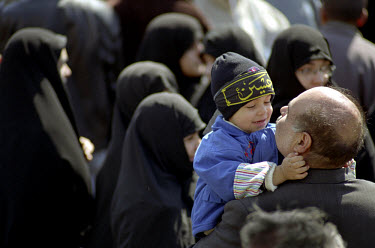 Father and son next to a crowd of women celebrating the Shia Islamic festival of Ashura.