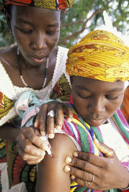 Immunisation session - a woman receiving a vaccination at an open air clinic.