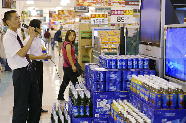A man demonstrates a karaoke machine in a supermarket.