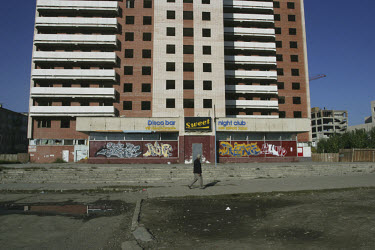 Man walking past a derelict bar and night club.