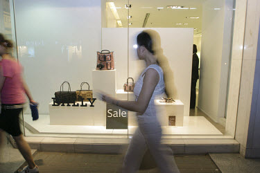 A woman glances into a shop window during sale time.