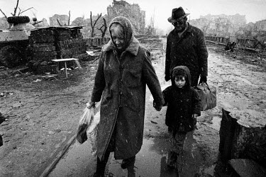 Chechen civilians walk through a checkpoint in the destroyed city after it was bombed and shelled by Russian forces during the invasion which began in December 1994.