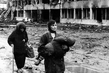Chechen civilians walk with a baby in arms out of the city after it was bombed and shelled by Russian forces during the invasion which began in December 1994.