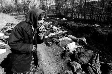 A woman searches for the bodies of her missing family members in a mass grave.