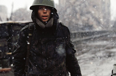 A Russian soldier stands in the city centre at a checkpoint amidst a snow storm.