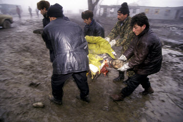 A victim of a bombing attack at a highway intersection is carried away by Chechens for identification and burial.