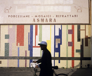 Man passing a mosaic. Asmara is a showcase of 1930s Italian Art Deco architecture. Initially created by colonial-era Italians, the style continued to flourish in the 1960s as local architects carried...