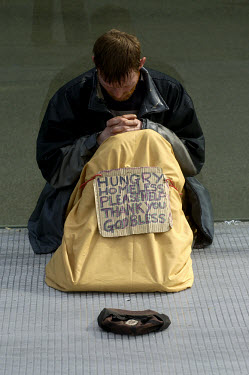 Homeless man begging on the MIllennium Bridge. His sign reads "Hungry Homeless Please Help God bless".