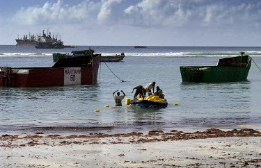 Porters using a small boat to unload jerrycans of cooking oil from cargo ships in the natural port of El�Mahaan, 30 km north of Mogadishu. Since the old sea port in the city was destroyed by fighting,...