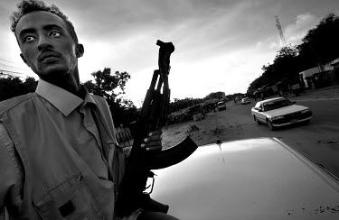 Gunman on top of a moving vehicle, providing an armed escort. Business is flourishing in Somalia despite more than a decade of anarchy, but each enterprise is dependent on the support of one of the cl...