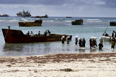 Porters using a small boat to unload sacks of wheat from cargo ships in the natural port of El�Mahaan, 30 km north of Mogadishu. Since the old sea port in the city was destroyed by fighting, this beac...