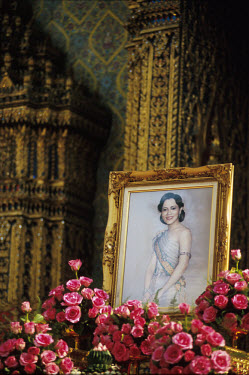 A photograph of Queen Sirikit, surrounded by roses in a temple.