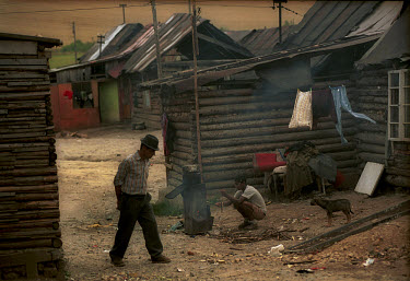 A man walks between log cabins in the Roma gypsy settlement of Rakusy, which has no running water or basic sanitation.
