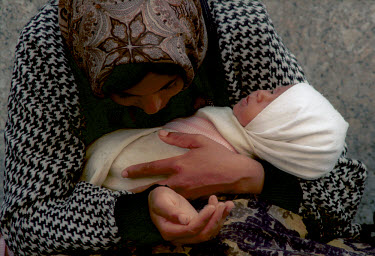 A Roma gypsy woman holding her baby as she begs on the street.